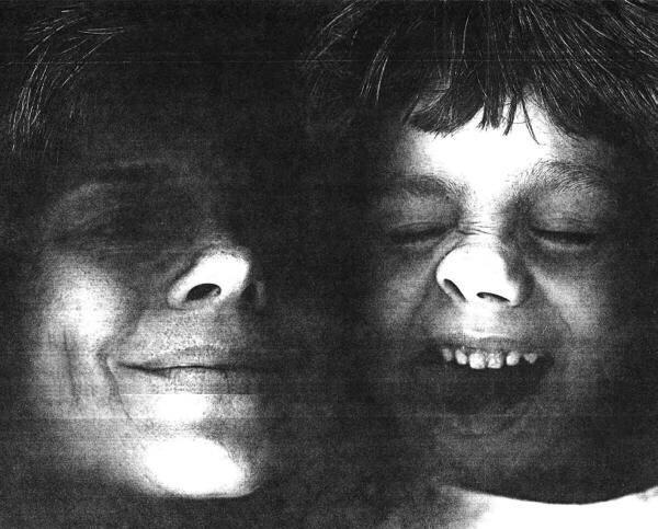 A close-up, black-and-white photo of an adult and a child. The adult is smiling softly, while the child laughs joyfully with eyes closed, highlighting their faces in contrasting shadows and light.