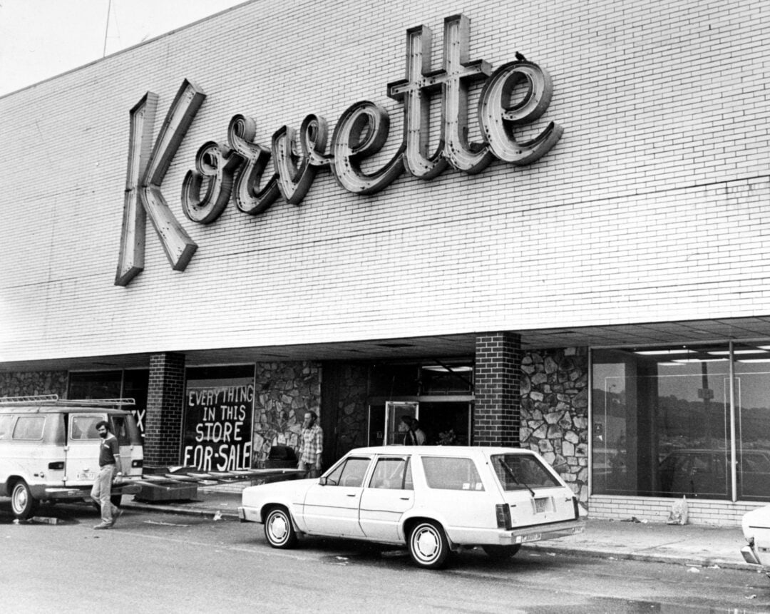 Black-and-white photo of a Korvette store with a large sign, cars parked in front, and a banner reading "Everything in this store for sale" hanging by the entrance.