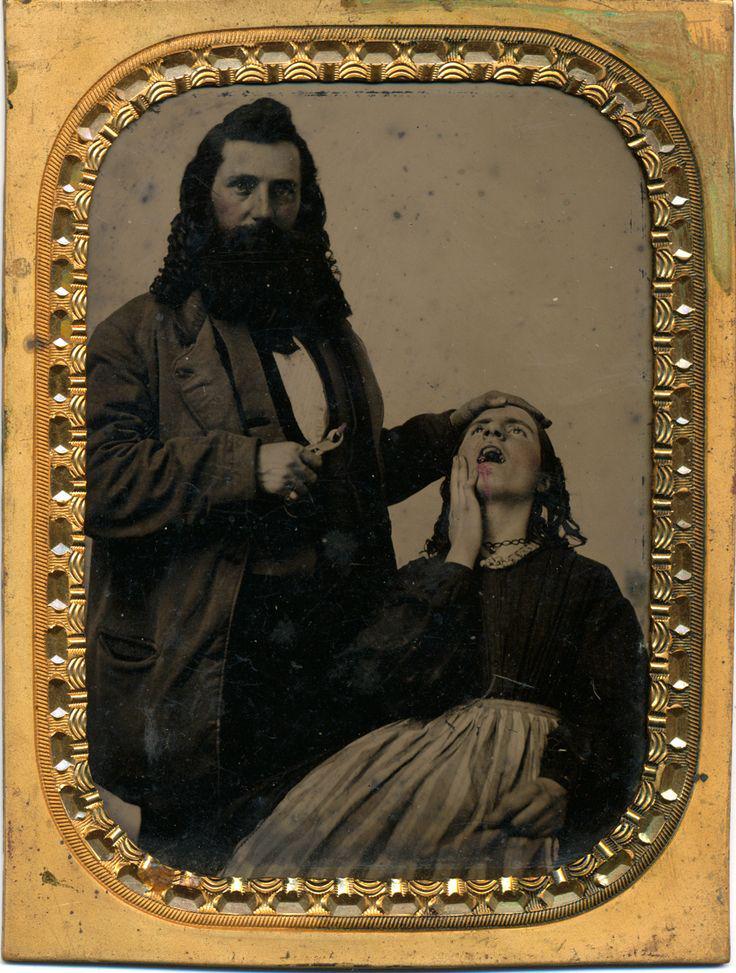 A sepia-toned vintage photograph shows a bearded man in 19th-century clothing holding dental pliers, poised to extract a tooth from a seated woman, whose mouth is open in pain. The ornate frame surrounds the image.