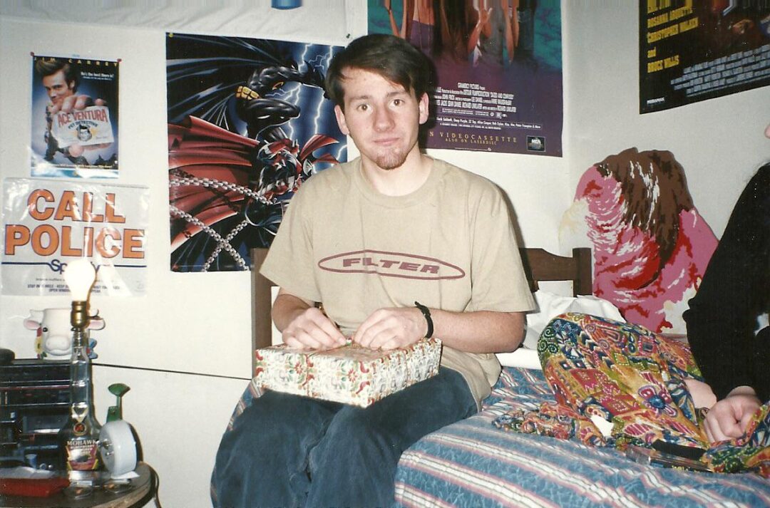 A man sitting on a bed holding a box