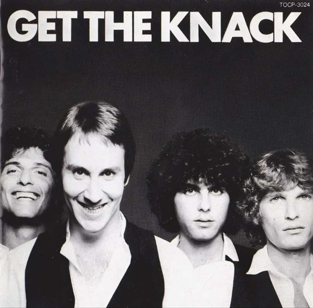 Four men in black and white attire stand side by side, smiling and looking at the camera, under bold white text that reads “GET THE KNACK.”