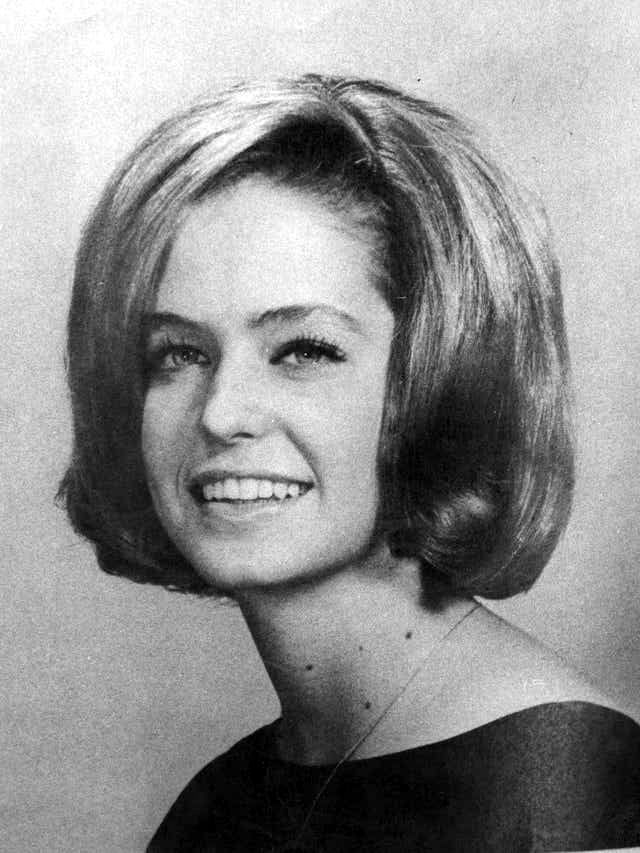 Black and white portrait of a young woman with a bob hairstyle, smiling and wearing a dark top. The photo appears to be from the mid-20th century.