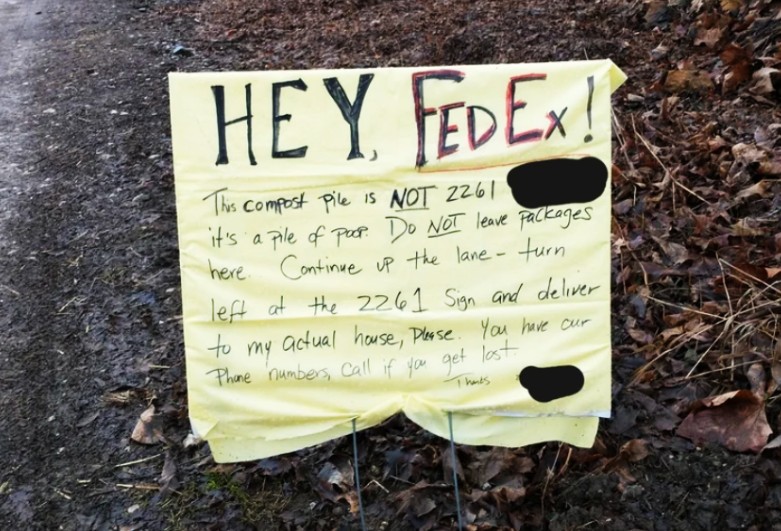 A handwritten yellow sign by a roadside directs FedEx not to leave packages at the current location, stating it's not 2261, but a compost pile. The note instructs drivers to deliver to the real house and includes redacted phone numbers.