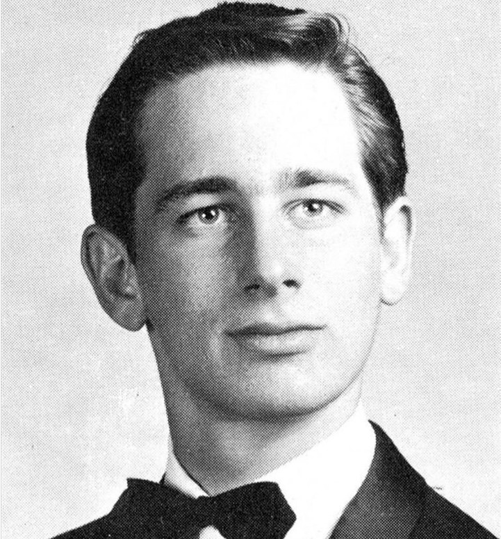 Black and white portrait of a young man with short hair, wearing a suit and bow tie, looking slightly to the side with a neutral expression.