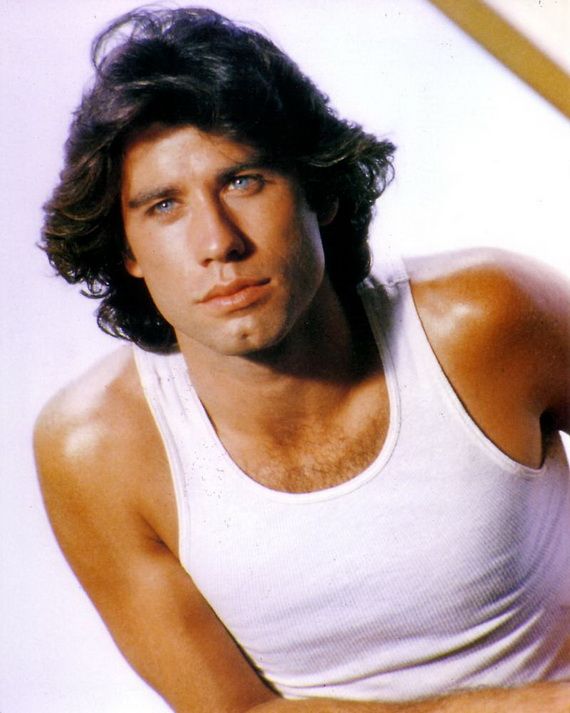 A young man with medium-length dark hair wearing a white tank top looks slightly to the side with a serious expression against a light background.