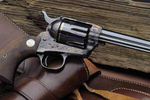 A classic revolver with a dark wooden grip lies atop a leather holster, with weathered wooden planks in the background.