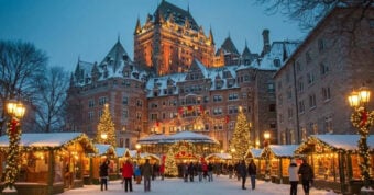 A festive outdoor Christmas market with decorated stalls, twinkling lights, and people walking in the snow. A grand, castle-like hotel adorned with lights rises in the background under a dusky winter sky.
