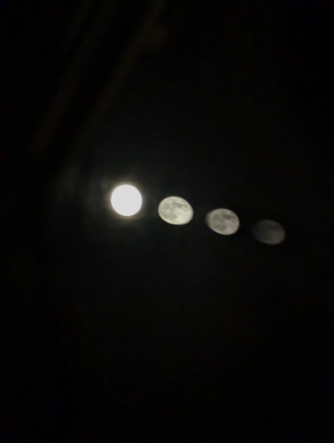 A blurred photo of the moon at night, showing four overlapping, progressively dimmer images of the moon in a line against a dark sky.