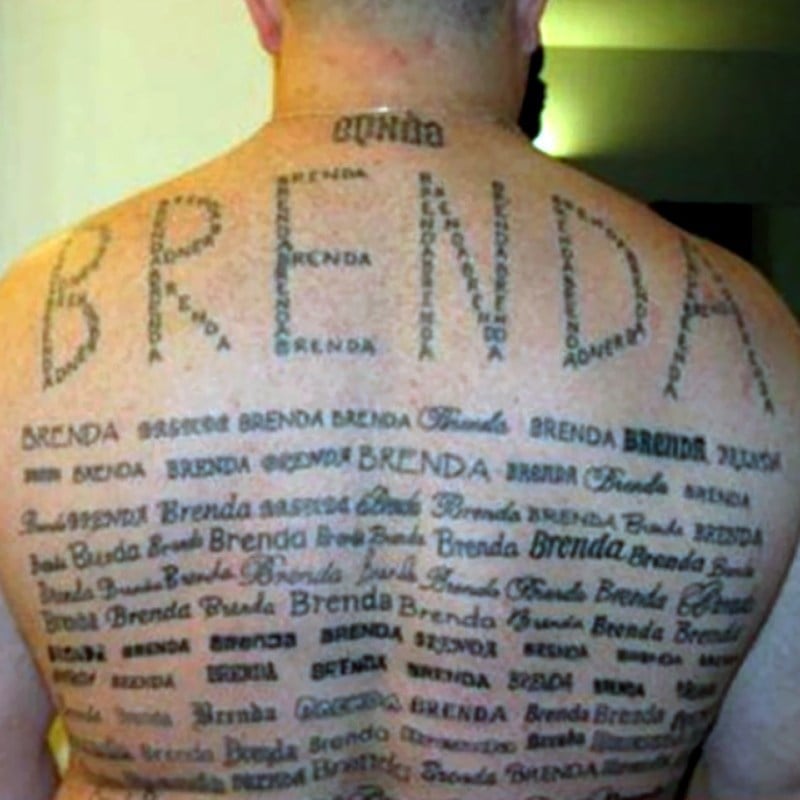 A man's back covered in numerous tattoos of the name "Brenda" in various fonts, sizes, and styles. The largest "BRENDA" is tattooed across the upper back, surrounded by many smaller versions.