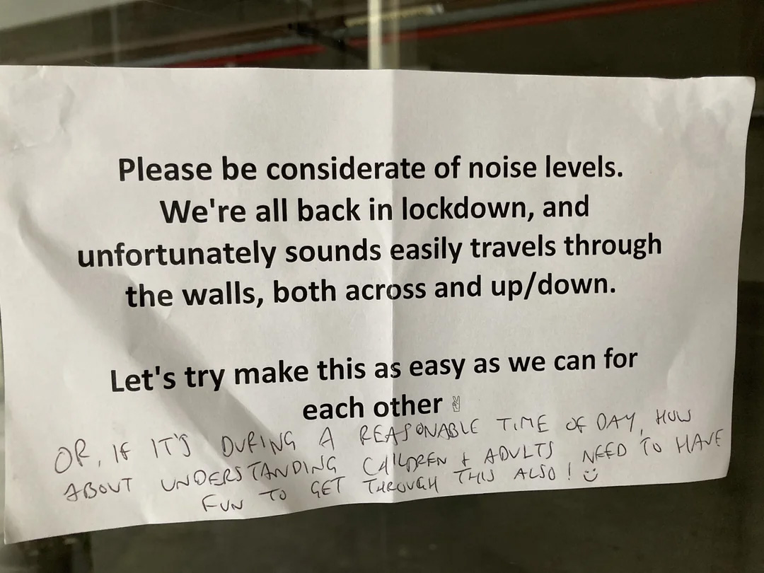 A printed sign asks people to be considerate of noise levels during lockdown, as sound easily travels through walls. A handwritten note below asks for understanding, as children and adults need fun to get through this time.