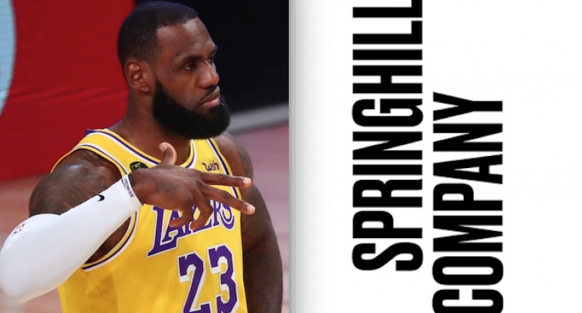 A basketball player in a yellow Lakers jersey with the number 23 gestures with his hand. Next to him, bold vertical text reads "SPRINGHILL COMPANY" on a white background.