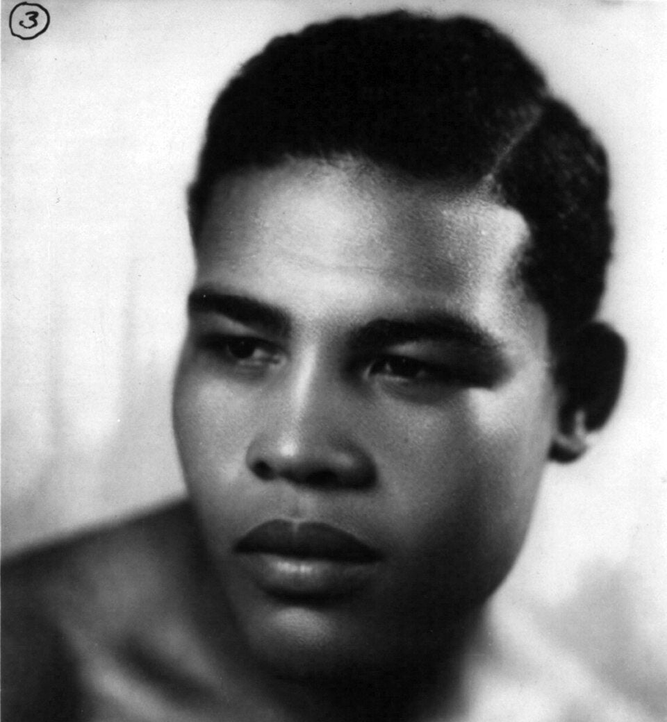 Black and white portrait of a young man with short curly hair, serious expression, and bare shoulders. Text at the bottom reads, “Joe Louis, Heavyweight Champion of the World.”