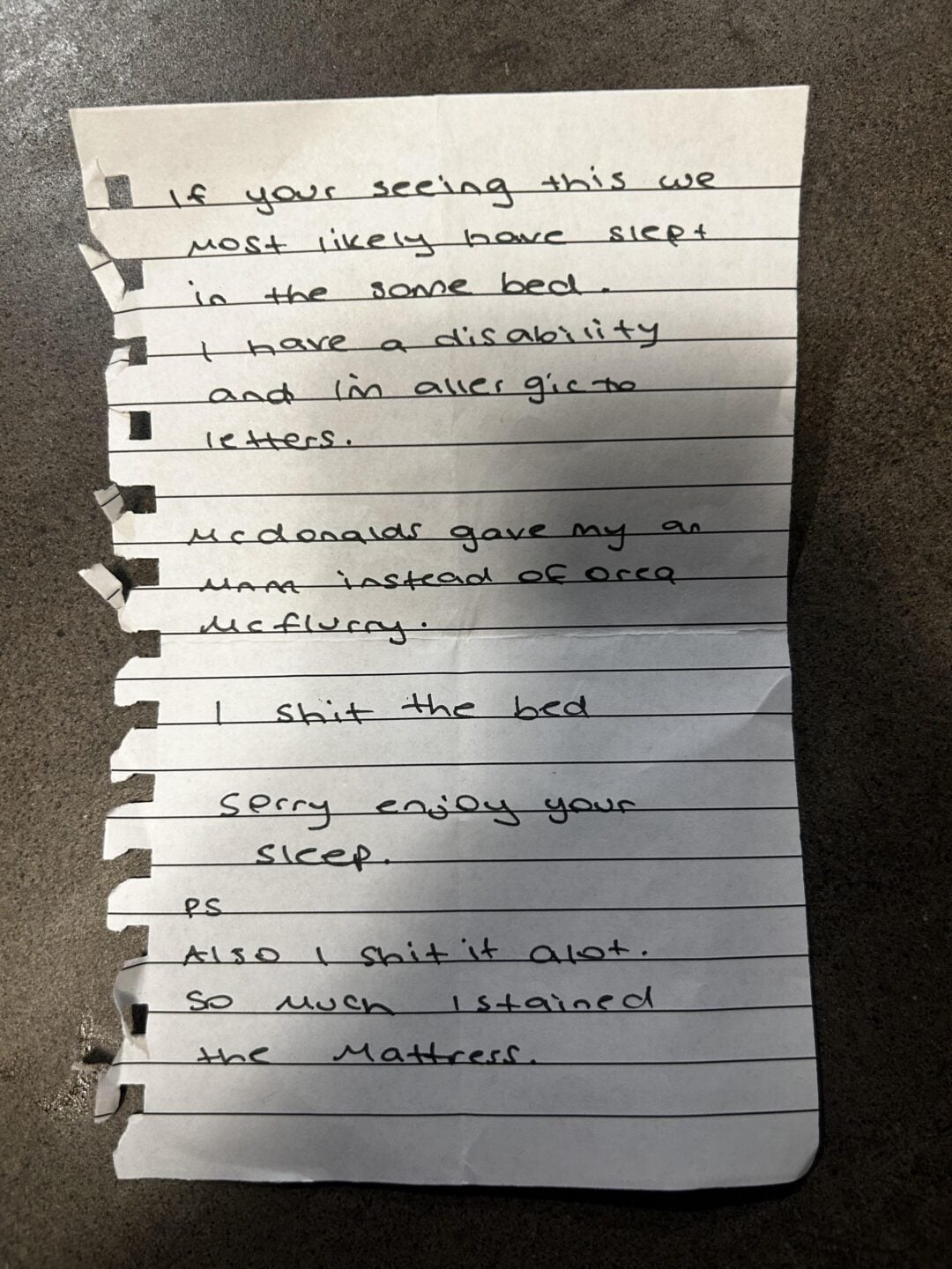 A handwritten note on torn notebook paper apologizes for staining the bed due to a disability and an allergic reaction after eating McDonald's. The writer mentions “shitting the bed” and warns the reader, ending with “sorry, enjoy your sleep.”