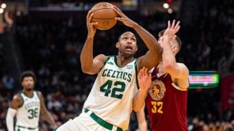 A Boston Celtics player wearing jersey number 42 prepares to shoot a basketball while being closely defended by a Cleveland Cavaliers player in a maroon jersey, during a game.
