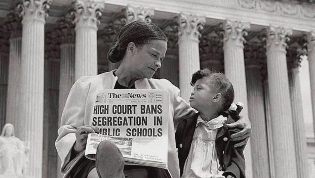 A Black woman holds a young girl on her lap and a newspaper headline reads, “High Court Bans Segregation in Public Schools.” They sit on steps in front of a large government building with columns.