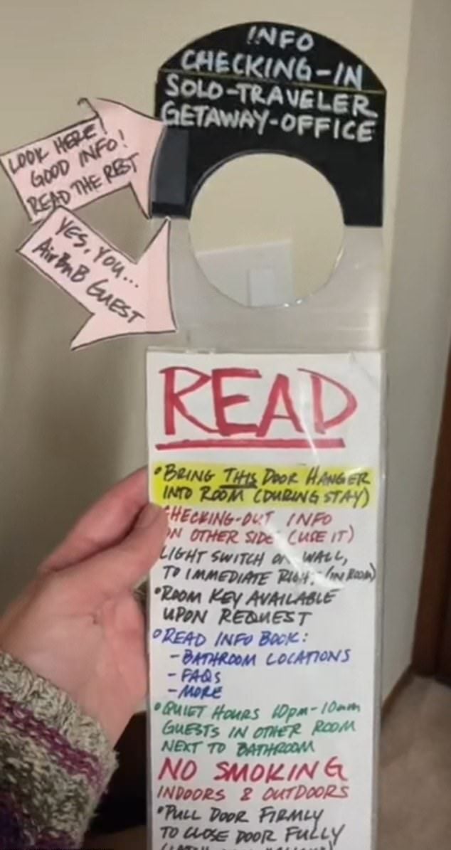 A person holds a door hanger sign with handwritten instructions titled "INFO CHECKING-IN SOLO TRAVELER GETAWAY OFFICE," featuring tips for guests, a "READ" heading, and details about room info, keys, and house rules.