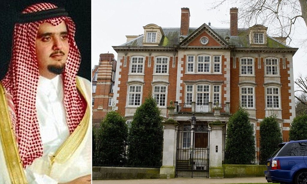 A man in traditional Middle Eastern attire is shown on the left. On the right is a large, multi-story brick mansion with white trim, tall windows, and a gated entrance, surrounded by trees and a parked car.