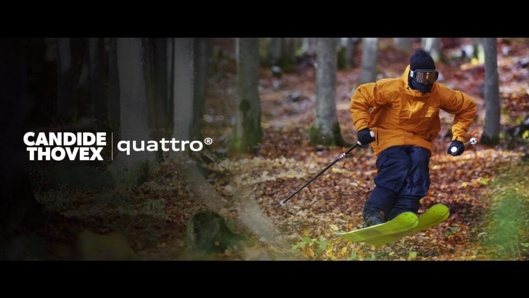 A skier in an orange jacket and black pants skis through a forest with autumn leaves on the ground. The text reads "Candide Thovex quattro" on the left side of the image.