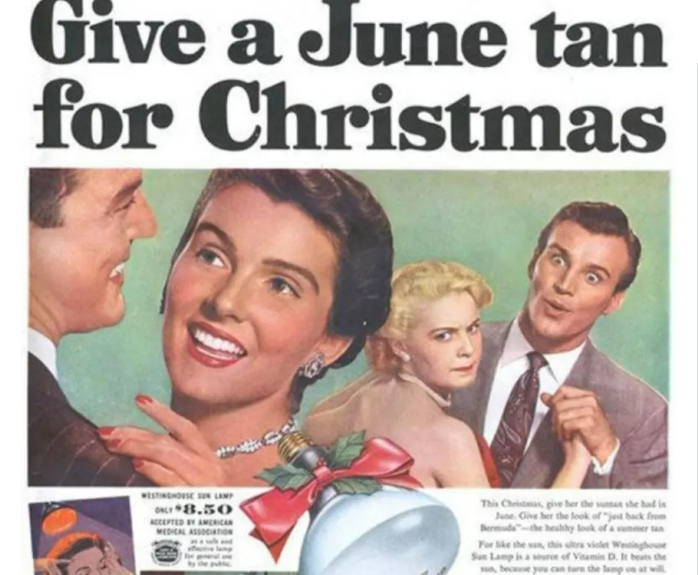 A vintage advertisement shows three smiling people with tanned skin, holding a sun lamp, alongside a blonde woman looking concerned. Bold text reads, "Give a June tan for Christmas.
