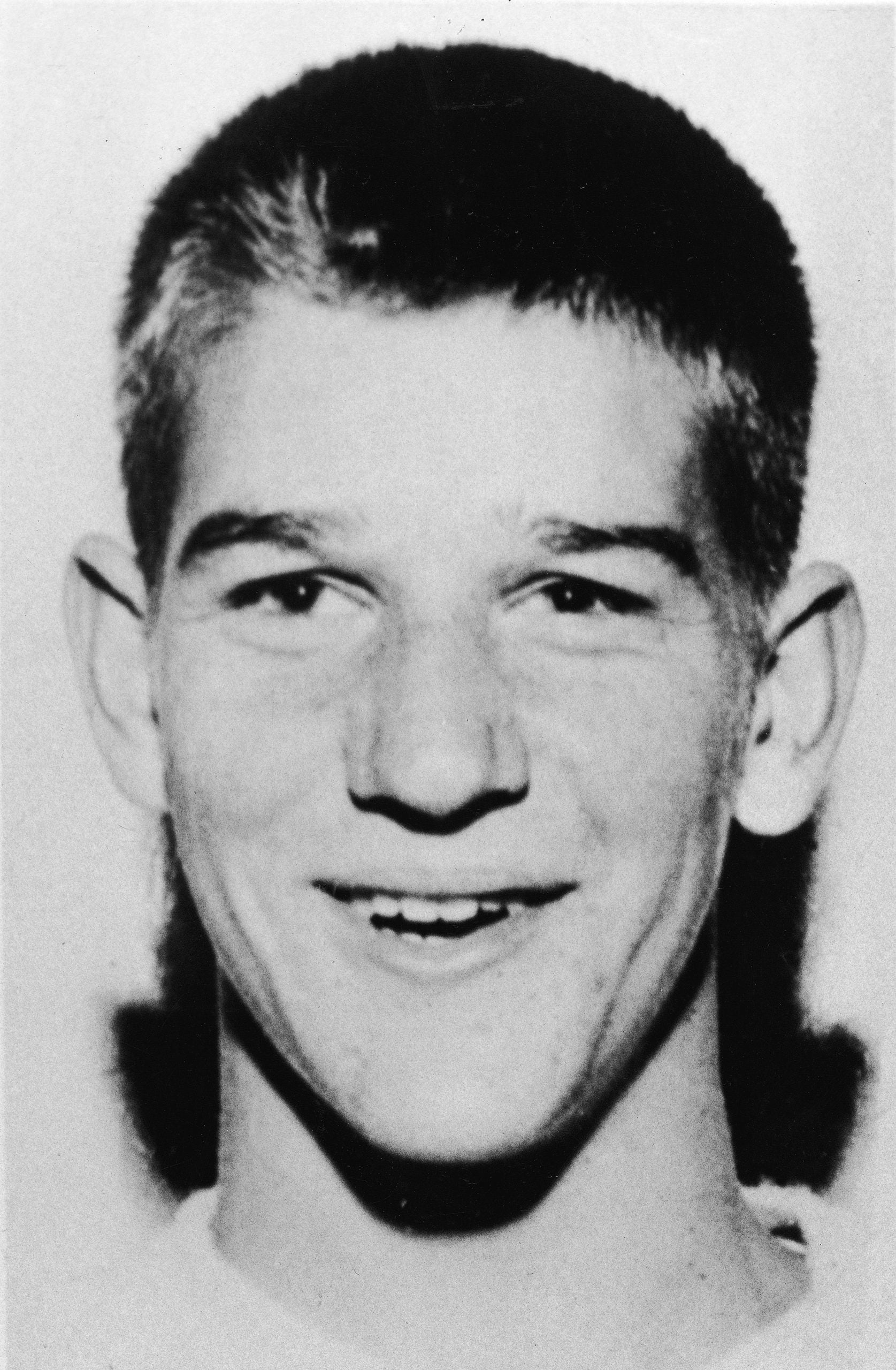 Black-and-white headshot of a young man with short hair, smiling, facing the camera. The background is plain and the lighting is even.