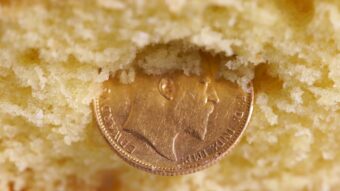 A gold coin partially embedded in the crumbly center of a yellow sponge cake.