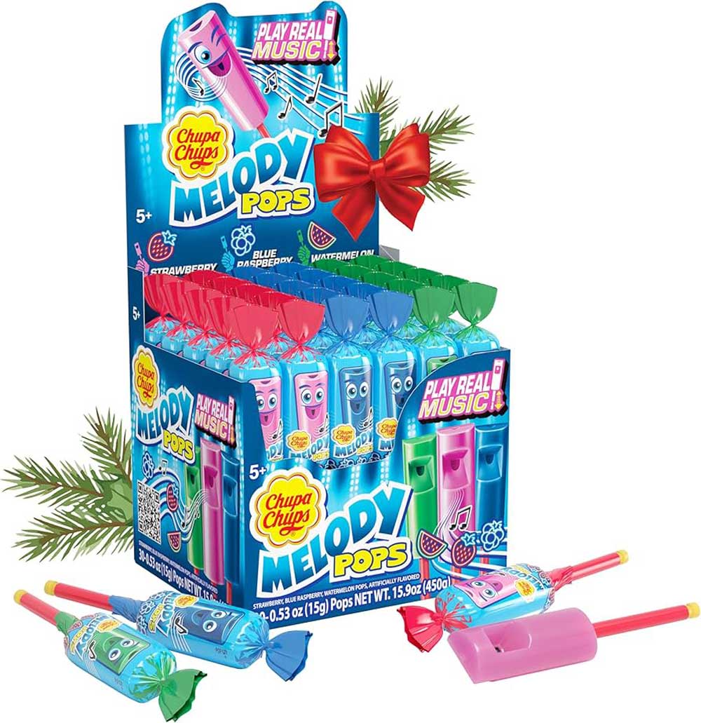 Box of Chupa Chups Melody Pops in colorful wrappers, displayed upright with some laid in front. The box is decorated with music notes, a red bow, and pine branches, and promotes that the candy can "play real music.