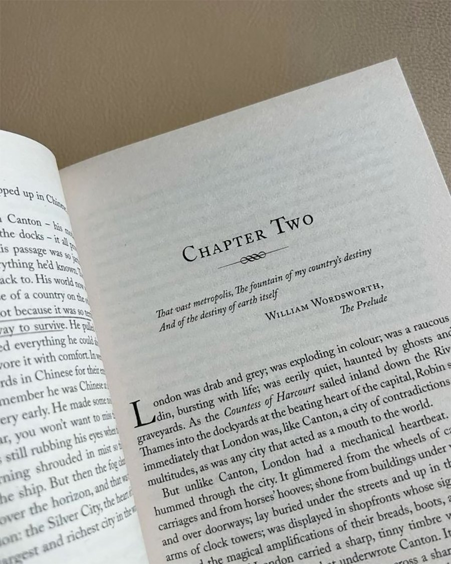 An open book showing the top of a chapter titled "Chapter Two" with a quote from William Wordsworth’s "The Prelude" and the beginning lines of text on a pale brown surface.