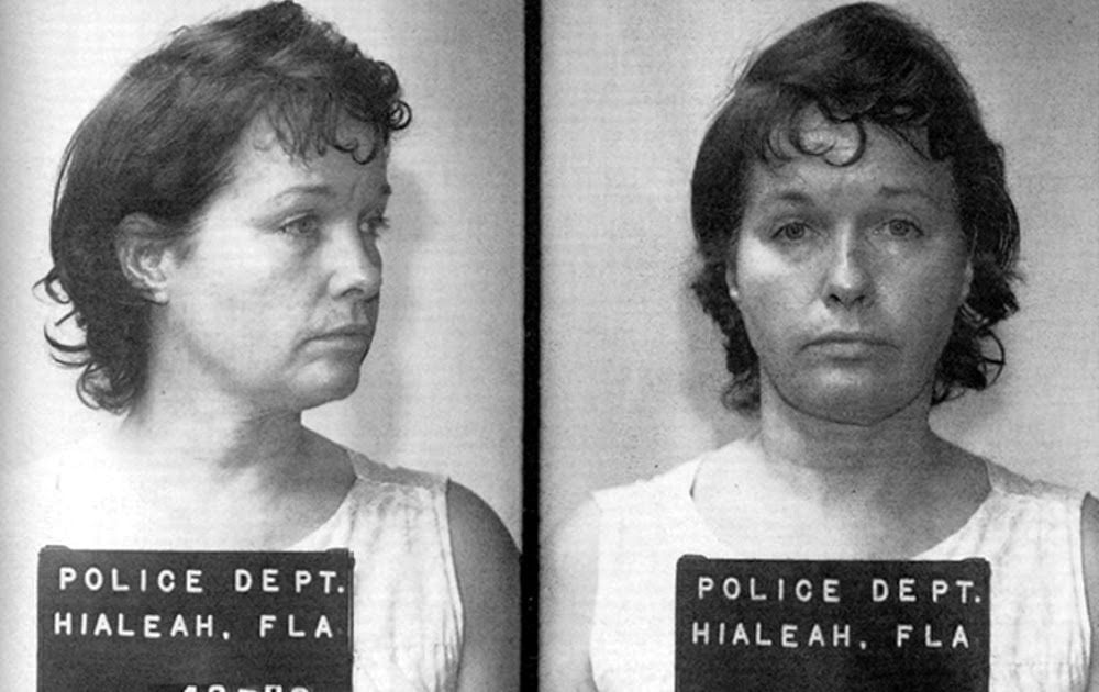 Black and white mugshot photo showing a woman with short, dark hair, wearing a sleeveless top, facing left in one image and looking straight at the camera in the other. Police Dept. Hialeah, Fla sign is visible.