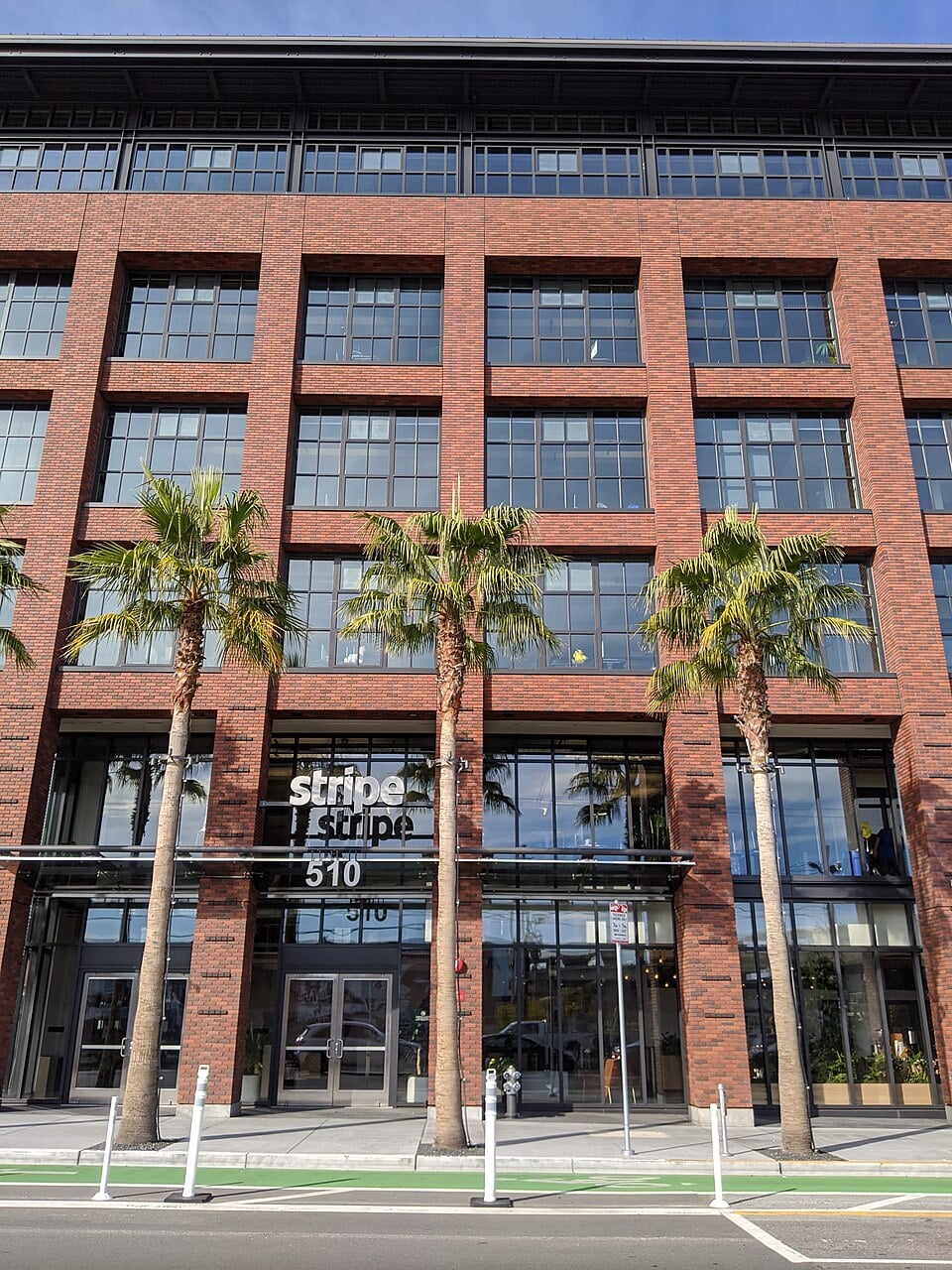 A brick office building with large windows and palm trees out front. The building has a sign that reads "Stripe" above the entrance at 510 Townsend Street.