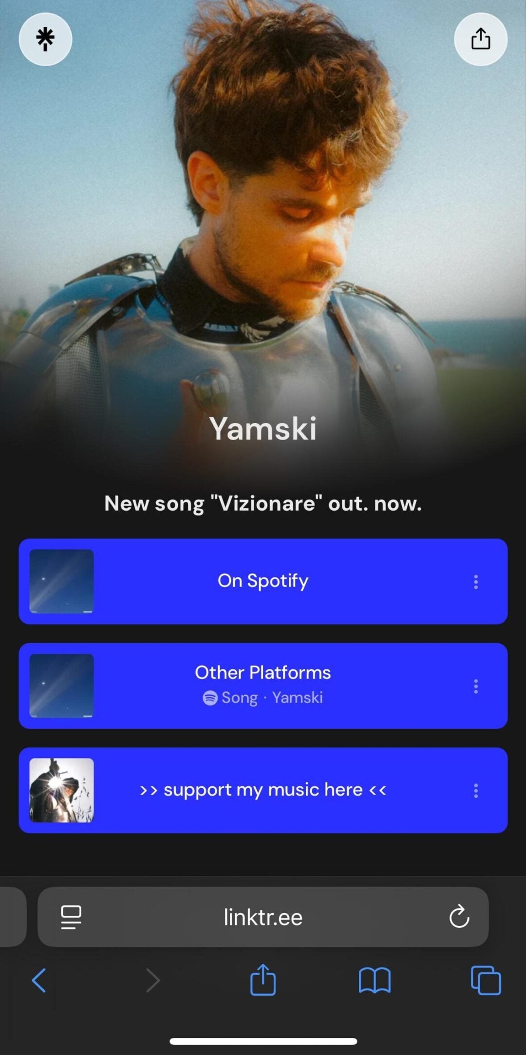 A man with light brown hair and a mustache looks down, standing outdoors under blue sky. Text reads "Yamski" with links to his new song "Vizionare" on Spotify and other platforms, plus a support link.