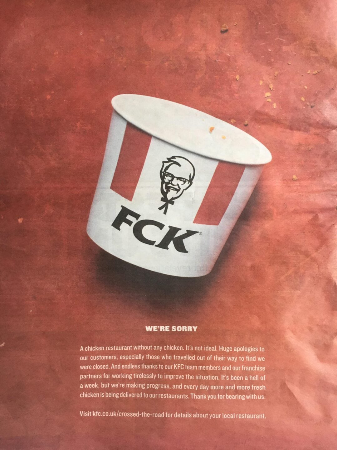 A KFC bucket with the logo misspelled as "FCK" is tilted on a red background. Text below reads "WE'RE SORRY" and explains an apology for restaurant closures and supply issues. Crumbs are scattered at the top.