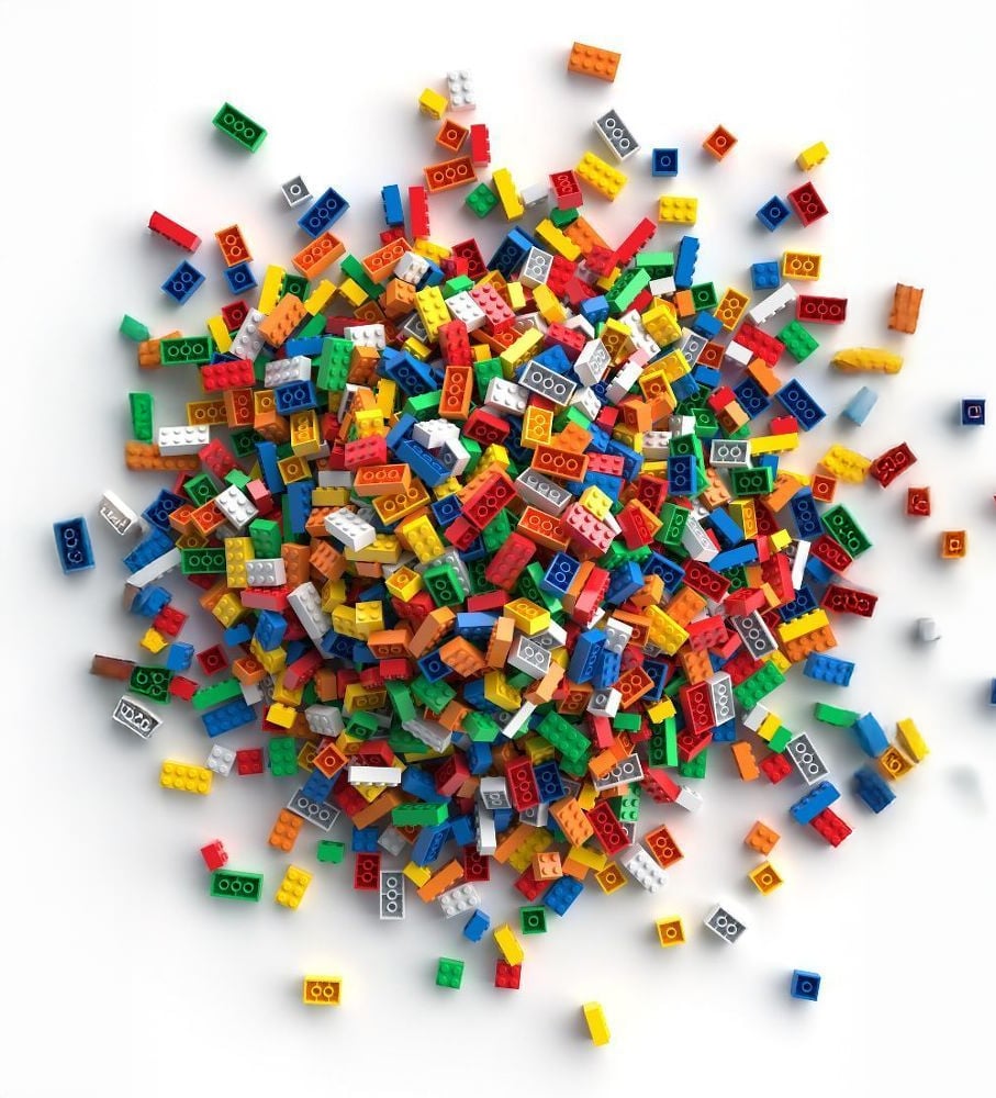 A large, scattered pile of colorful plastic LEGO bricks in various shapes and sizes on a white background.