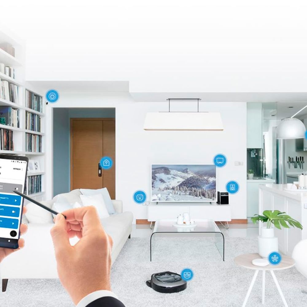 A person uses a smartphone to control smart home devices in a modern living room, with icons indicating connected features like lights, locks, TV, and a robotic vacuum on the floor.