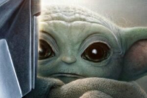 A close-up of the Mandalorian in shiny armor and Grogu (Baby Yoda) looking toward the viewer. Text reads: "The Mandalorian and Grogu. May 21. Only in theaters.