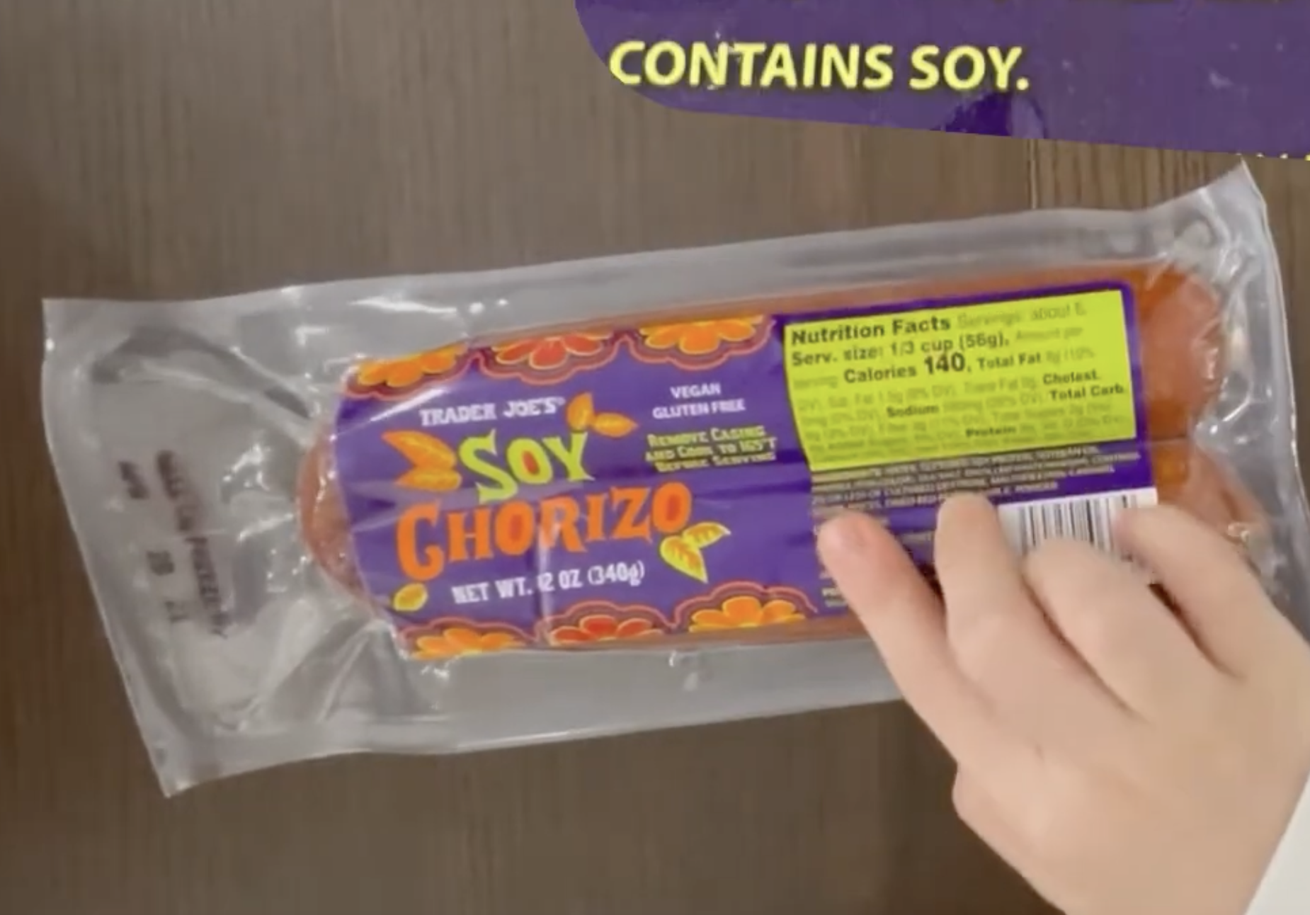 A hand holds a 12-ounce package of Trader Joe’s Soy Chorizo, with text at the top stating “Contains soy.”