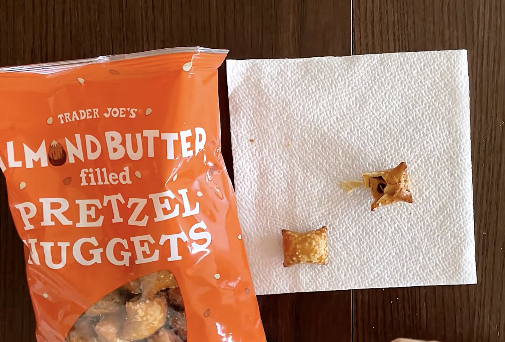 A bag of Trader Joe’s almond butter filled pretzel nuggets next to two pretzel nuggets on a paper towel.