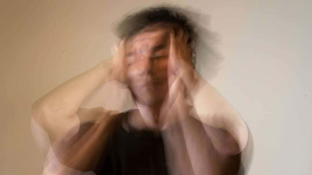 A blurry image of a person holding their head with both hands, suggesting distress, confusion, or anxiety. The motion blur creates a sense of movement and emotional turmoil.