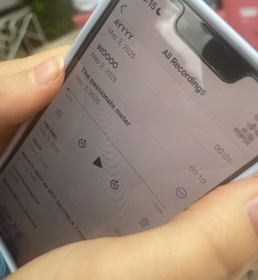 A close-up of hands holding a smartphone, displaying a screen with voice recordings titled "AYYYY," "WOOOO," and "The Passionate meter," all dated May 3, 2025.