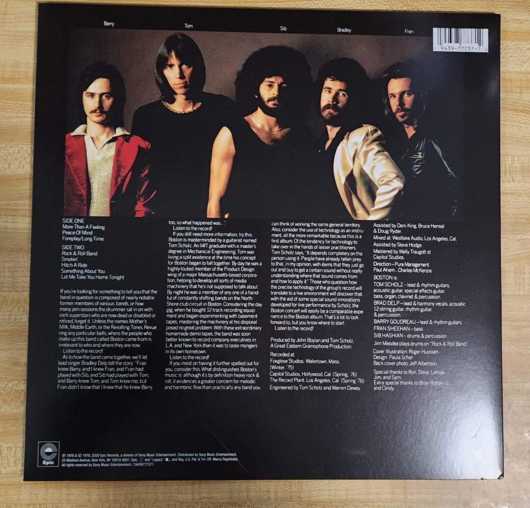 Five men stand closely together against a dark background on the back cover of a music album. Text with song titles, credits, and acknowledgments is printed beside and below them.