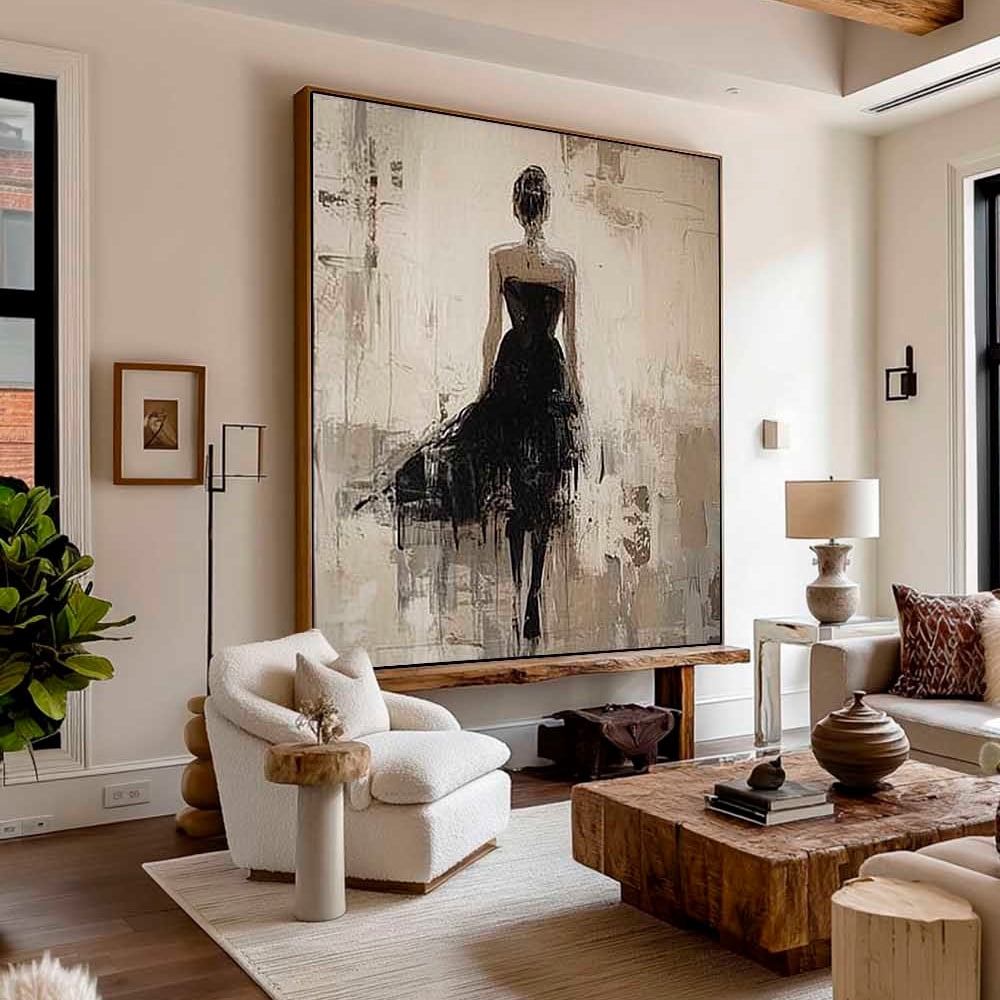 A modern living room with neutral decor features a large abstract painting of a woman in a black dress on the wall. The space includes a white armchair, wooden coffee table, and natural light from large windows.