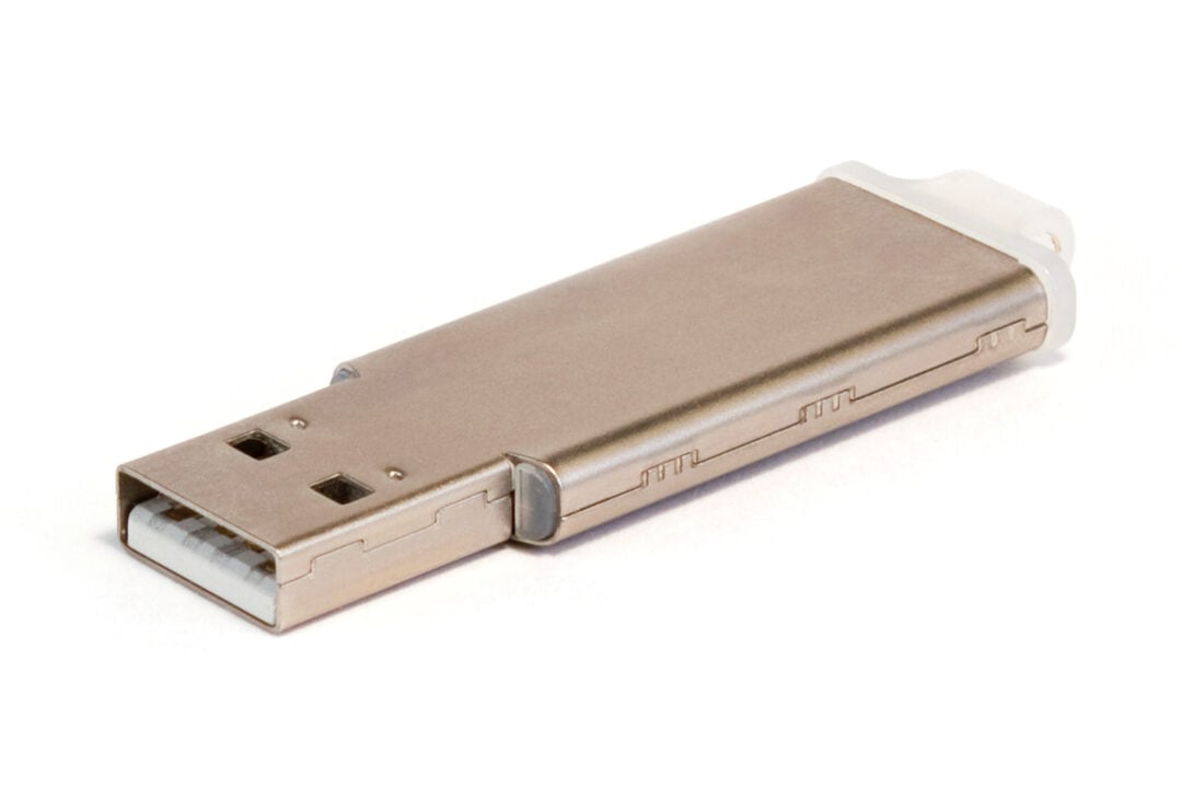 A metallic USB flash drive with a rectangular shape featuring a visible USB connector and a small clear plastic cap resting on a white background.