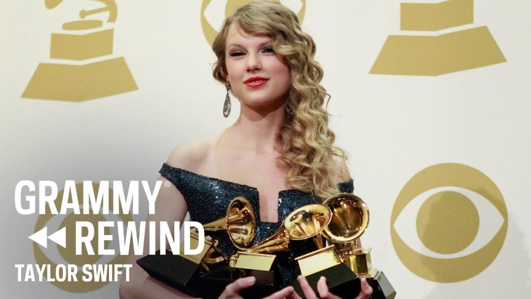 Taylor Swift wearing a sparkly dress, holding multiple Grammy Awards and smiling in front of a backdrop with Grammy and CBS logos. Text on the image reads "GRAMMY REWIND TAYLOR SWIFT.