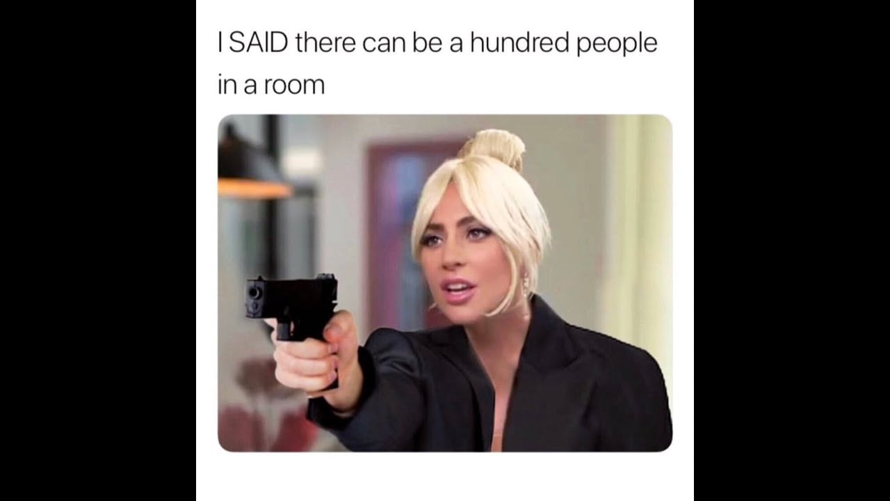 A woman with blonde hair in a black outfit points a handgun forward, looking serious. Text above reads, “I SAID there can be a hundred people in a room.”