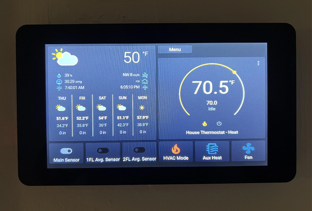 A touchscreen thermostat display shows the current outdoor temperature as 50°F with a weather forecast. The indoor temperature is 70.5°F. Various controls and settings are visible on the screen.