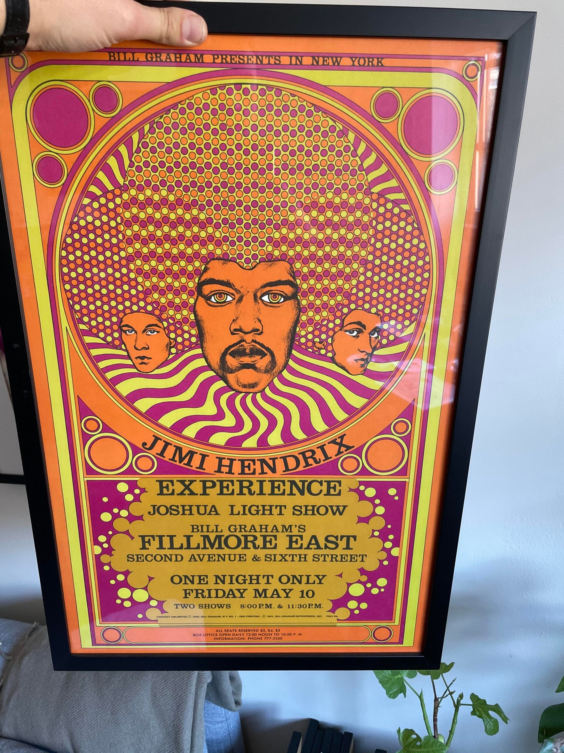 A framed psychedelic concert poster featuring Jimi Hendrix's face with vibrant orange, yellow, and pink swirls, promoting the Jimi Hendrix Experience at Fillmore East on Friday, May 10.
