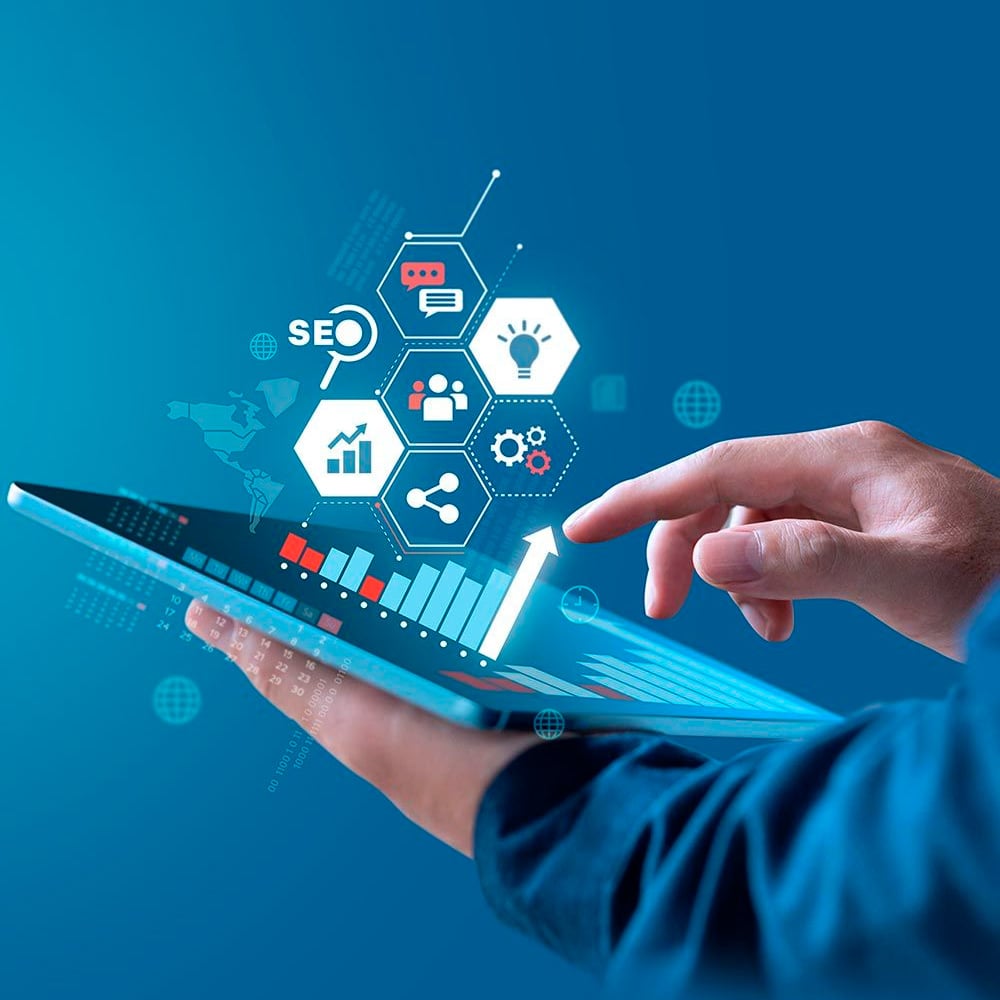 A person uses a tablet displaying rising bar charts and digital icons for analytics, technology, and communication, symbolizing data analysis and business growth on a blue background.