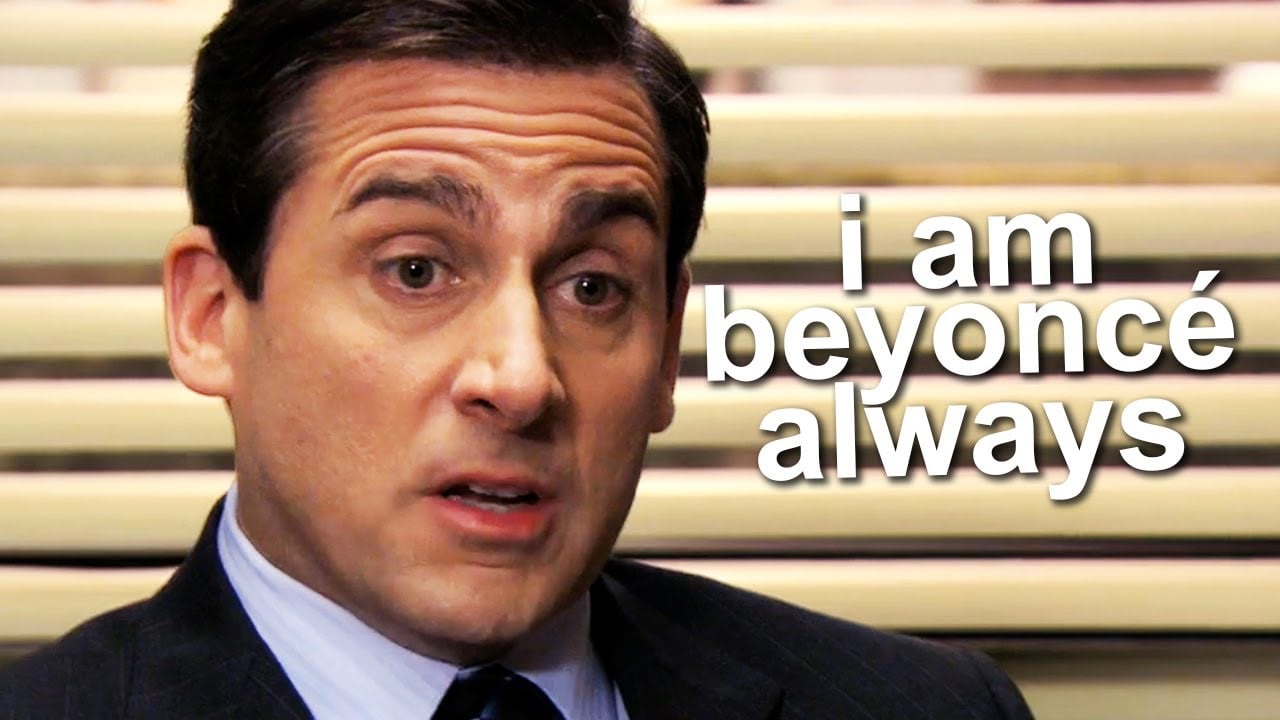 A man in a suit looks serious while sitting in front of beige blinds. White text beside him reads, "i am beyoncé always.