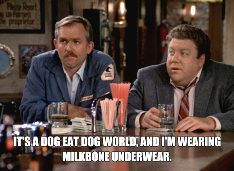 Two men sit at a bar with drinks; one wears a blue jacket, the other a suit and tie. Text on the image reads: "It’s a dog eat dog world, and I'm wearing Milkbone underwear.