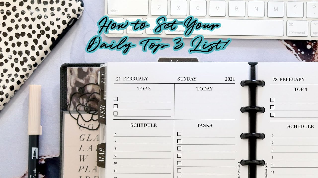 An open planner displaying a checklist for tasks and schedules, with the heading “How to Set Your Daily Top 3 List!” above it. A pen, keyboard, and patterned notebook are also visible in the background.