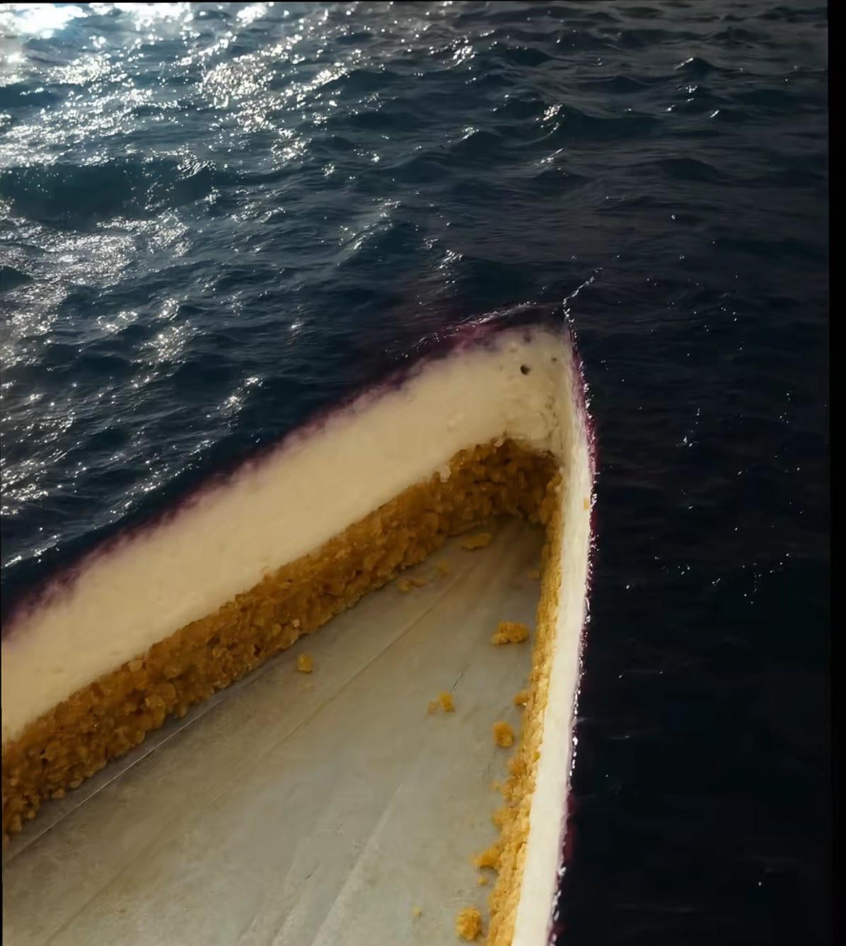 A close-up view of the bow of a small, empty boat floating on dark, rippling water. The boat has a white interior with a yellowish edge and appears weathered.